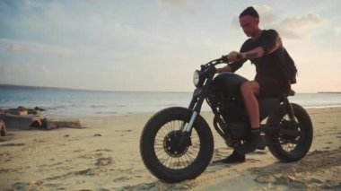 Onun motosiklet sahilde günbatımı sırasında sürüş motosikletçi. Ağır çekim.