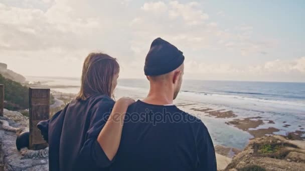 Una mujer joven con su novio, el jinete y su motocicleta admiran juntos la maravillosa vista alrededor, la montaña y las vistas al mar — Vídeos de Stock