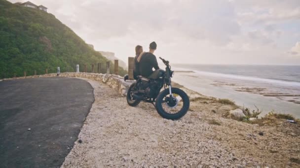 En ung kvinna med hennes pojkvän, ryttaren och hans motorcykel tillsammans beundra den underbara utsikten runt, utsikt över bergen och havet — Stockvideo