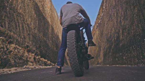Motociclista dirigindo sua moto Entre duas pedras na praia do oceano — Vídeo de Stock
