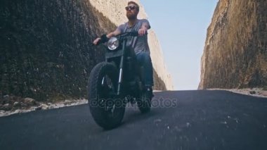 Okyanus plaj iki taş arasında onun motosiklet sürüş motosikletçi