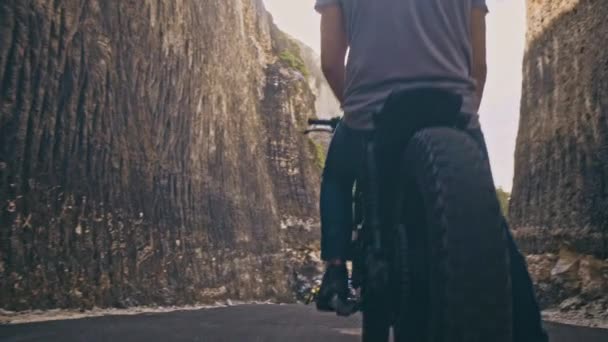 Motociclista dirigindo sua moto Entre duas pedras na praia do oceano — Vídeo de Stock