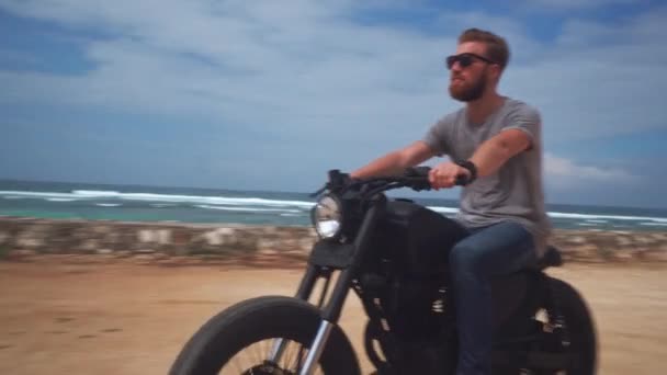 Мотоцикліст за кермом свого мотоцикла на океанському пляжі — стокове відео