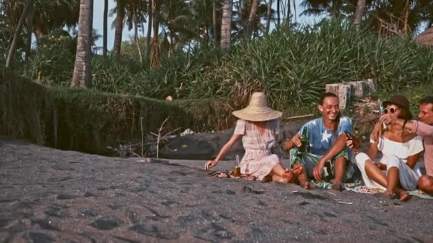 Grupp av vänner har roligt avkopplande på stranden vid solnedgången — Stockvideo