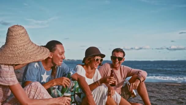 Grupo de amigos divirtiéndose relajándose en la playa al atardecer — Vídeos de Stock