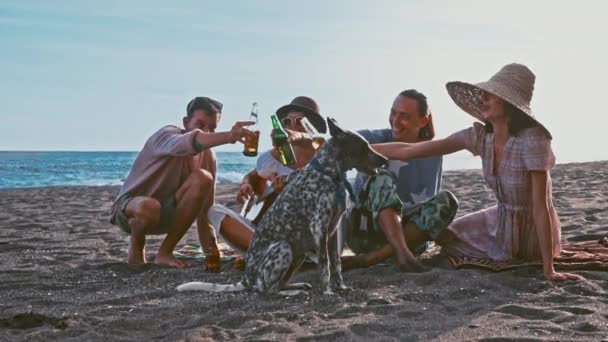 Jóvenes divirtiéndose en la playa. Fin de semana en la isla. Compañía de amigos divertida cantando con una guitarra y un perro divertido. Picnic en la playa. Campaña juvenil — Vídeos de Stock