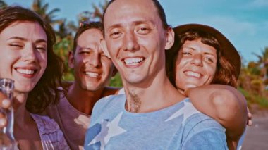 Grup dört kaygısız çekici mutlu arkadaşıyla dışarıda eğleniyor. Dostluk kavramı. Kucaklayan ve okyanus plaj üzerinde gülüyor birlikte kalıyorum, kameraya, seyir gülümseyen arkadaş grubu