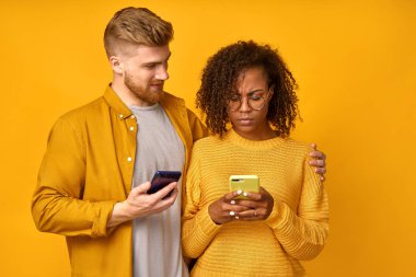 Hüsrana uğramış üzgün Afrikalı kadın cep telefonu tutuyor, elektronik e-posta faturasını görünce şaşırıyor, medya dosyalarında indirme arıyor, sevecen arkadaş kucaklıyor ve sakinleştirmeye çalışıyor.