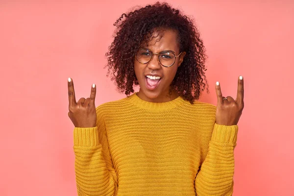Spännande glad ung afroamerikansk kvinna lyfter humöret från hög musik, visar heavy metal rock gest, glad att besöka konsert favoritband, utropar högt med glädje. Ja, jag känner mig cool och fantastisk. — Stockfoto
