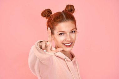 Genç kızıl kadın pembe arka planda bir parmağını gösteriyor. Jest sayılıyor