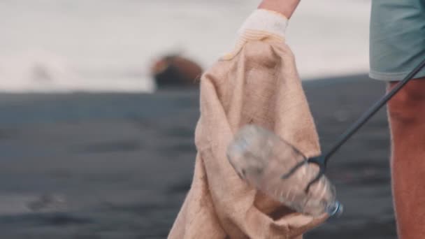 Hombre recogiendo residuos de plástico con un palo de recogida de basura en la bolsa de basura ecológica — Vídeos de Stock