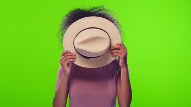 Zwarte vrouw met strohoed bewegen en ziet er met zelfverzekerde expressie op de camera — Stockvideo