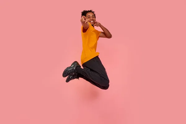 Largometraje completo de joven sorprendido hombre de piel oscura saltando en el aire y señalando, eligiendo algo, aislado sobre fondo de estudio rosa. Libertad de elección, inspiración, concepto de emociones humanas — Foto de Stock