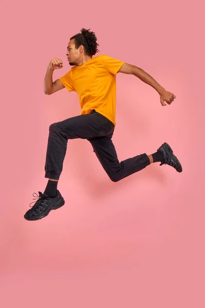 Full length side profile body size photo funky funny African American he him his guy jump high rush shopping black friday low prices wear casual black jeans orange t-shirts isolated pink background — Fotografia de Stock