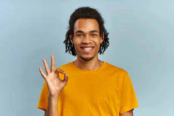Afričan se dívá do kamery, spokojený klient s úsměvem ukazuje ok gesto — Stock fotografie