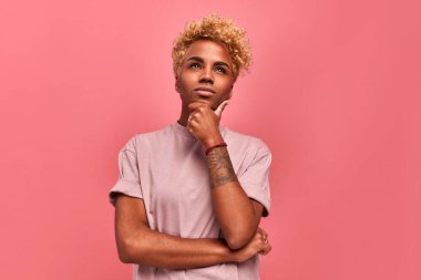 Bir düşüneyim. Düşünceli, koyu tenli, sarı saçlı, çantalı, dudaklı, eli çenesinin altında olan, bir şeyler planlayan, karar veren, pembe arka planda duran bir kadın. Şüphe kavramı