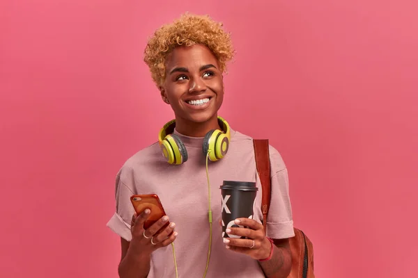 Vrolijke jonge glimlachende Afrikaans-Amerikaanse student die take-away koffie — Stockfoto
