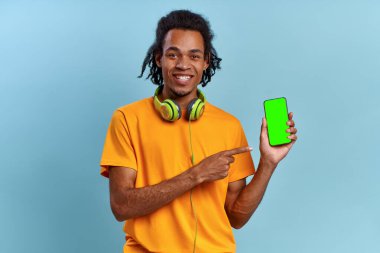 Gülen melez adam yeşil ekran akıllı telefonunu işaret ediyor.