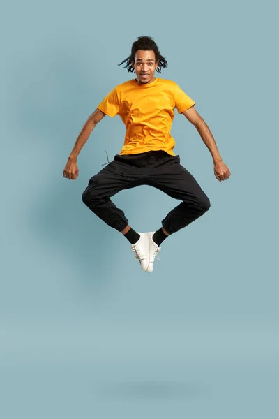 Pieno colpo di lunghezza di uomo nero felice in arancione t-shirt salto e guardando verso l'alto — Foto Stock