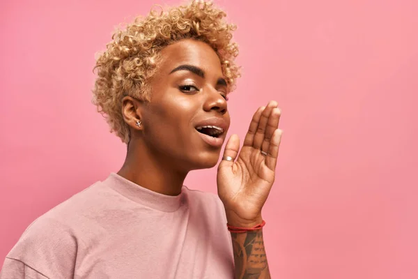 Mujer africana con pelo rubio sobre fondo de estudio rosa gritar con felicidad. — Foto de Stock