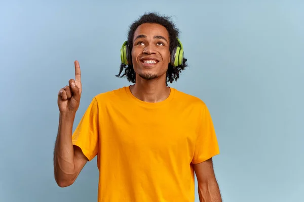 원문 기사보기 긍정적 인 젊은 힙합 학생인 아프리카 계 미국인 음악 팬 이 무선 헤드폰 노란색 티셔츠를 손에 들고 있다. 맨 위에 있는 링크와 설명의 개념. 광고의 공간 — 스톡 사진