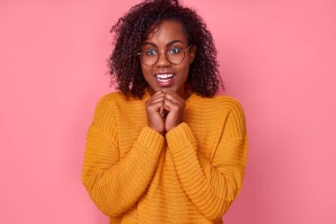 Heyecanlı, neşeli, Afro-Amerikan genç bir kadının portresi. Pembe stüdyo arka planındaki düşük alışveriş fiyatlarından çok memnun bir sürpriz bekliyor. Hediye ve ikramiye kavramı. Reklam alanı