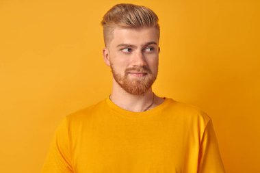 Sarı arka planda sakallı, yakışıklı, beyaz bir adamın portresi sağa bakıyor. Çevrimiçi mağazadaki erkekler için reklam malları ve hizmetleri kavramı. Metin için yer