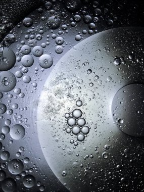 Sudaki baloncuk yağı uzayda bir gezegene benzer, koyu arkaplanda tam ışık vardır..