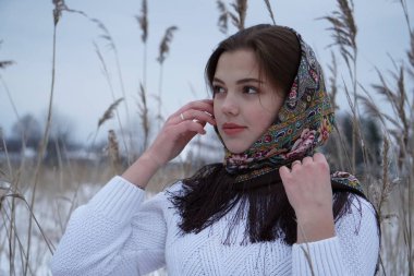 Beyaz kazaklı bir kızın portresi ve doğanın arka planında açık iş şalı.