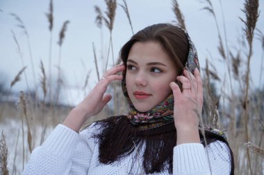 Beyaz kazaklı bir kızın portresi ve doğanın arka planında açık iş şalı.