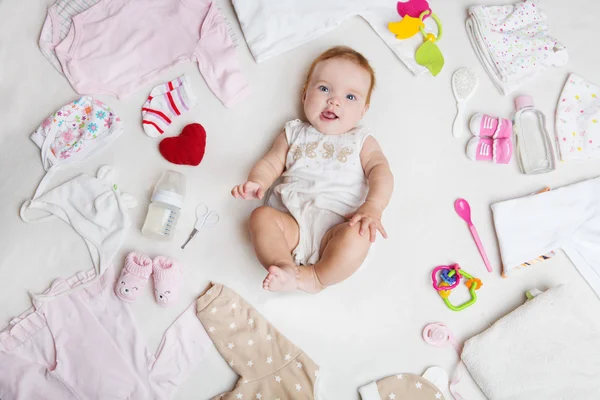 Baby na bílém pozadí s příslušenstvím, oblečení, toaletní potřeby, hračky a zdravotní péči. Seznam nebo nakupování přehled pro těhotenství a miminko. — Stock fotografie