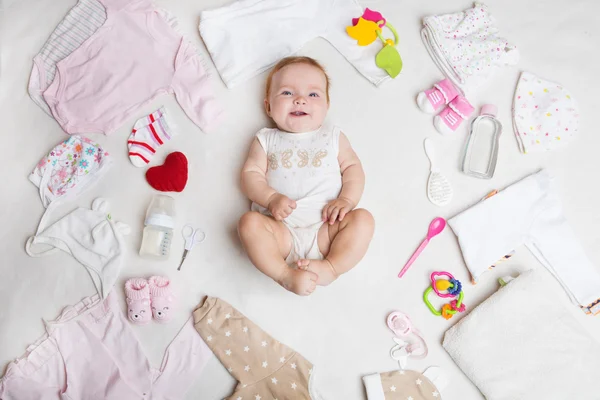 Baby na bílém pozadí s příslušenstvím, oblečení, toaletní potřeby, hračky a zdravotní péči. Seznam nebo nakupování přehled pro těhotenství a miminko. — Stock fotografie