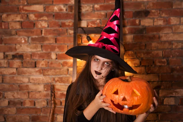 Vtipné dítě dívka v kostýmu čarodějnice na Halloween s dýně Jack — Stock fotografie
