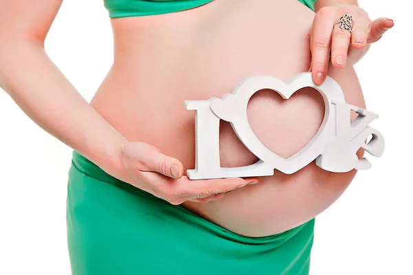 Belly of a pregnant woman in a green dress, mother hands with the word love — Stock Photo, Image