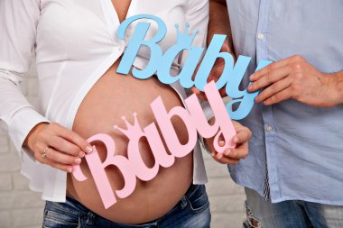 Karın hamile bir kadın, babası ve annesi kelime bebek tutan eller