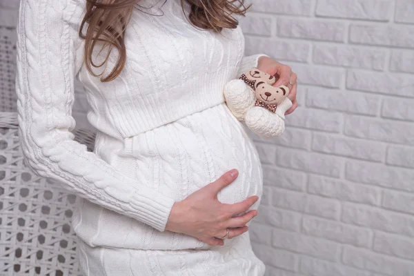 Ventre de femme enceinte avec des chaussons blancs — Photo