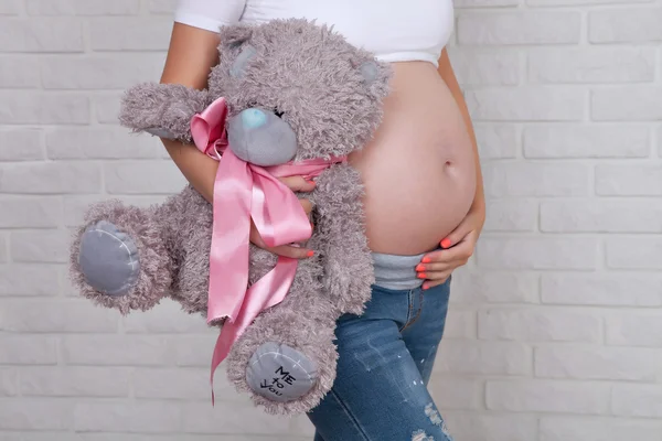 Ventre d'une femme enceinte avec un ours en peluche — Photo