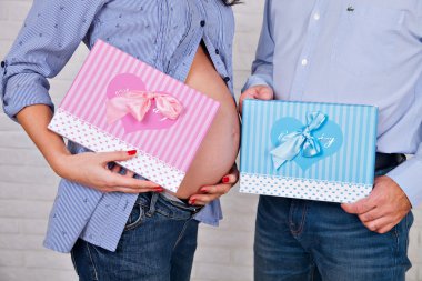 Genç aile bebek, el baba ve anne için bekleyen bir pembe ve mavi kutu hediyeler, yeni doğan erkek ya da kız ile tutarak tutmak