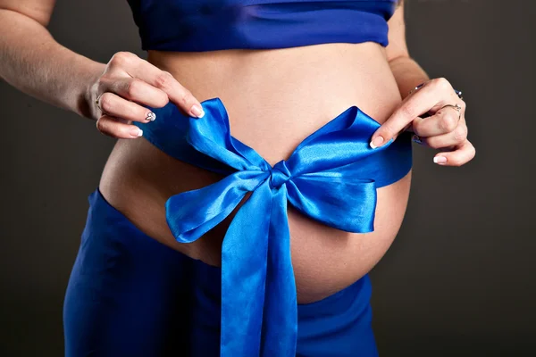 Ventre de femme enceinte avec arc bleu, garçon nouveau-né — Photo
