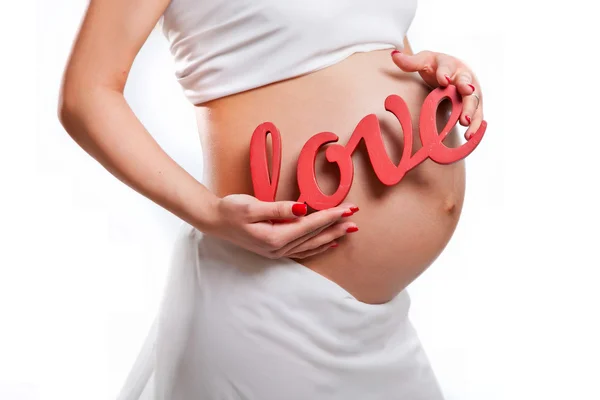 Ventre d'une femme enceinte, main de mère avec le mot amour — Photo