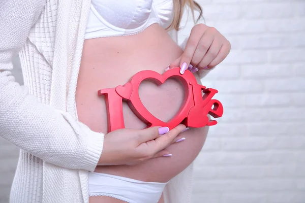 Belly of a pregnant woman,mother hand with the word love — Stock Photo, Image