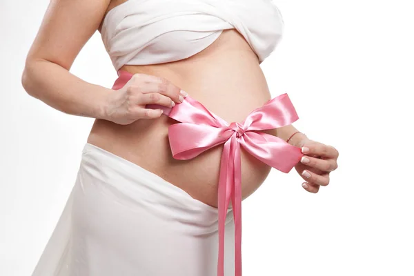 ピンクの弓を持つ妊婦のおなか 新生児の女の子 — ストック写真