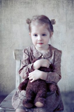 Kitaplı, gözlüklü, gülümseyen küçük kız.