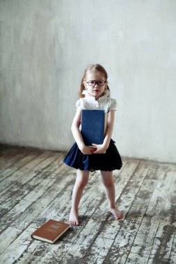 Kitapları olan, gözlüklü küçük bir kız.