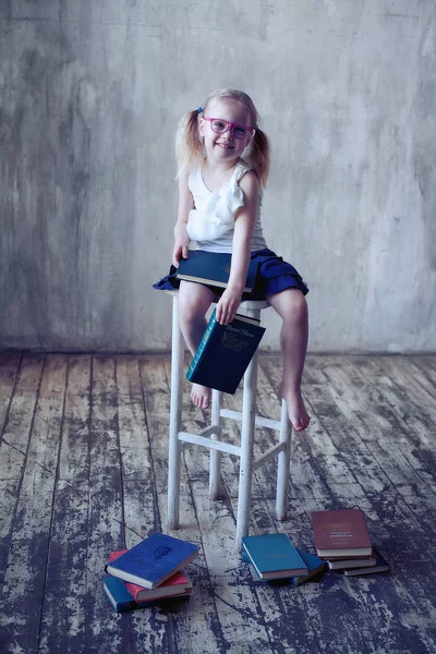 Kitaplı, gözlüklü, gülümseyen küçük kız.