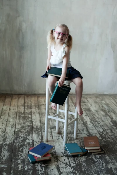 Kitaplı, gözlüklü, gülümseyen küçük kız.