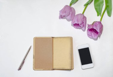ahşap zemin üzerinde telefon ve laleler olan notlar için not defteri