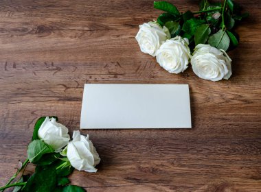 Tahta arka planda beyaz güller olan tebrik kartı.