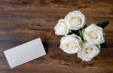 Tahta arka planda beyaz güller olan tebrik kartı.