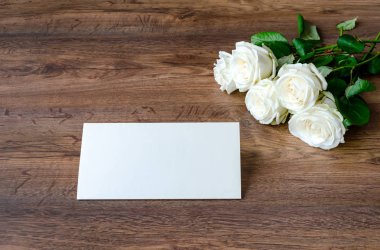 Tahta arka planda beyaz güller olan tebrik kartı.